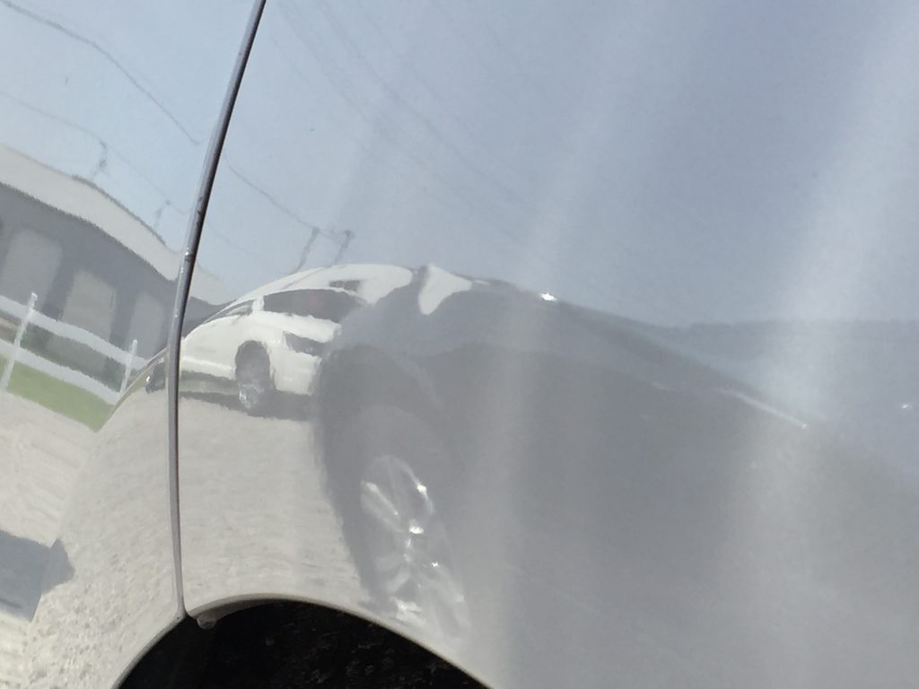 The white rear quarter panel of a 2015 tri-coat white Ford Edge after a body line dent repair
