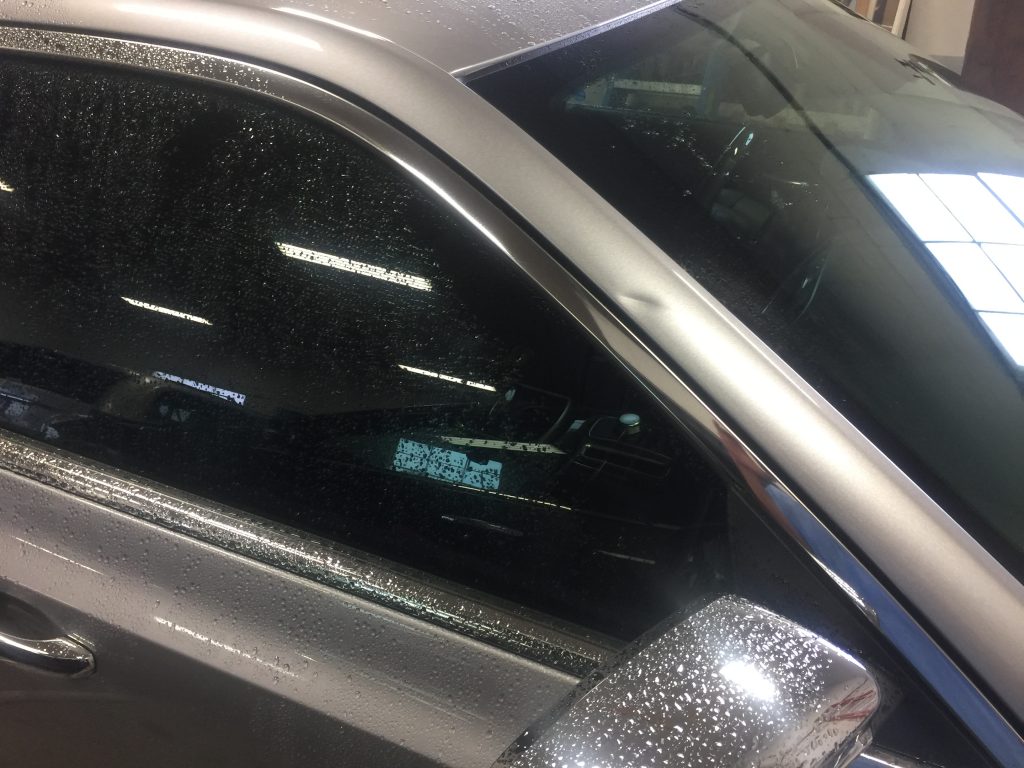 The passenger pillar area of a silver 2015 Chrysler 300 with a deep crease