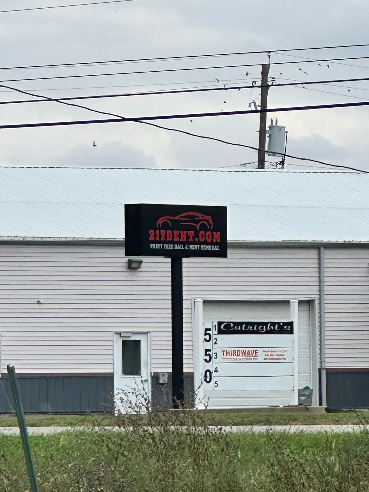 The 217 Dent sign standing in front of a white metal-sided building with a garage door, next to the 550 address panel at 550 North Street in Springfield, Illinois