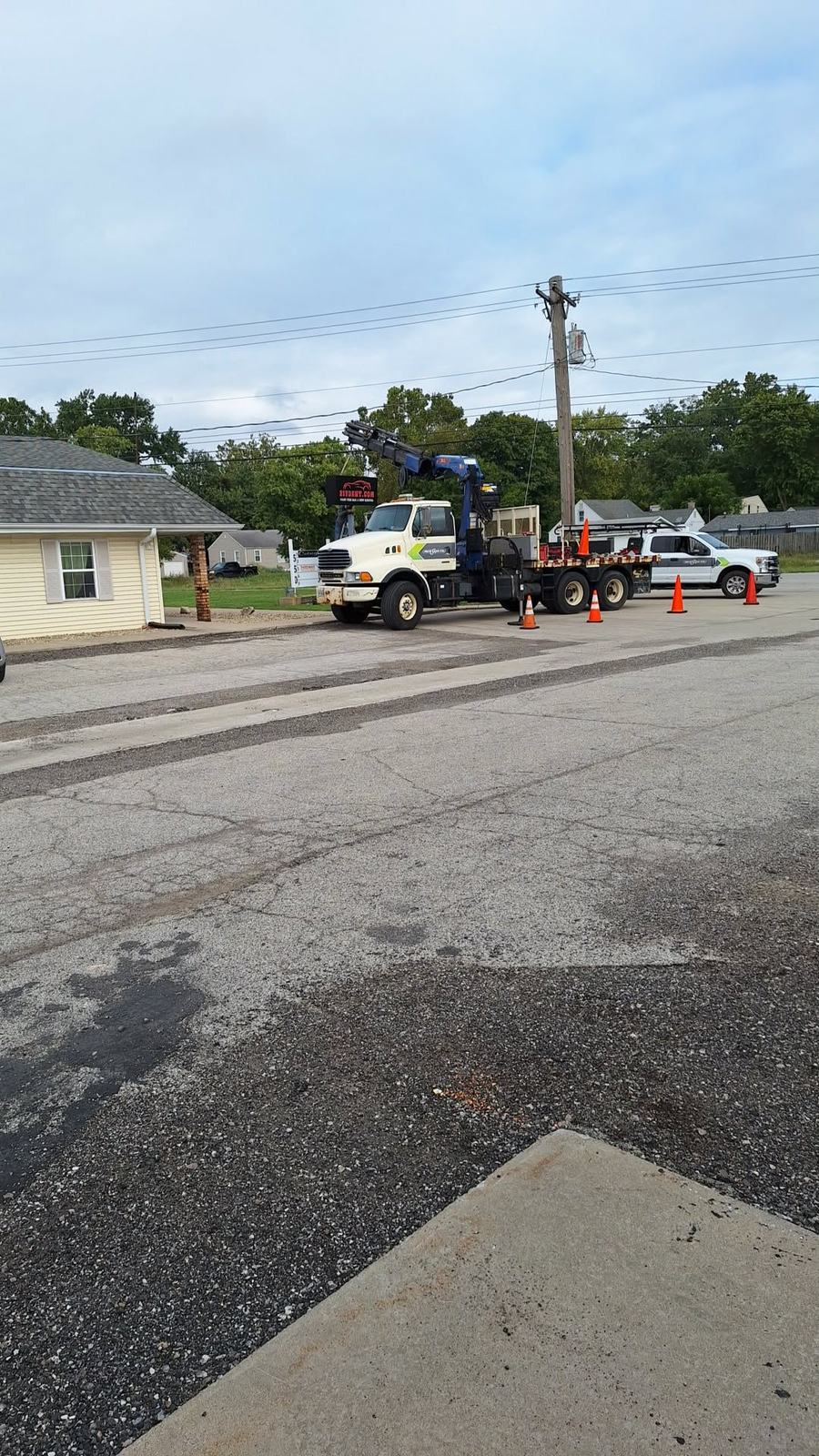 A crane truck parked with orange traffic cones set out around it, installing the 217 Dent sign