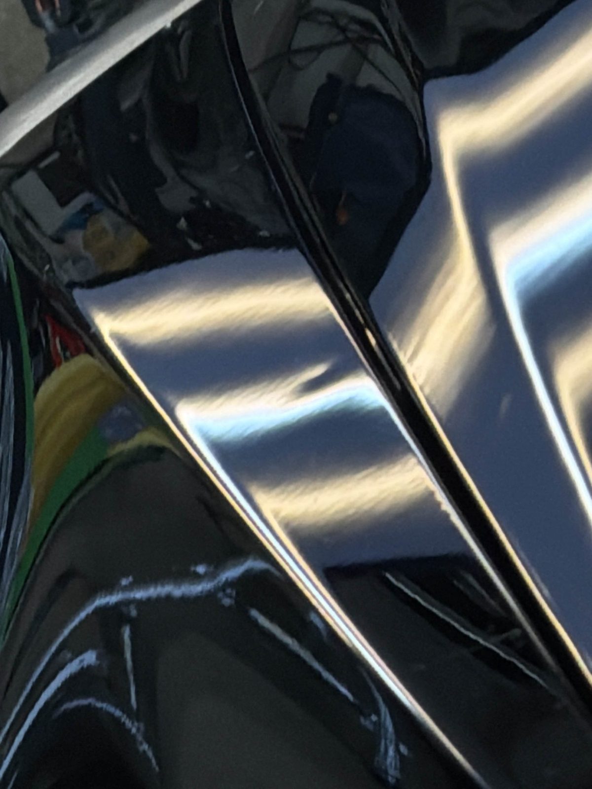 Steel driver fender of a black Cadillac CTS Sport Wagon with reflection lines broken by hail dents