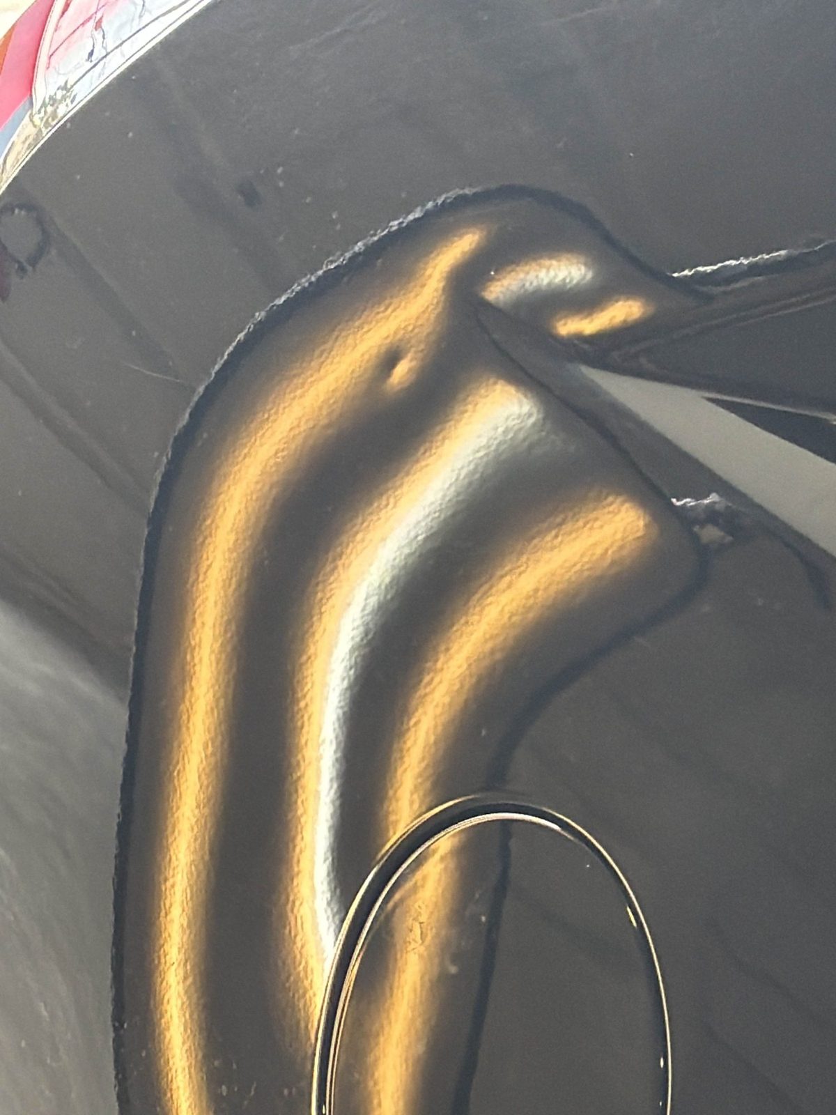 Passenger quarter panel of a black Cadillac CTS Sport Wagon at the fuel door, hail dents in the light lines