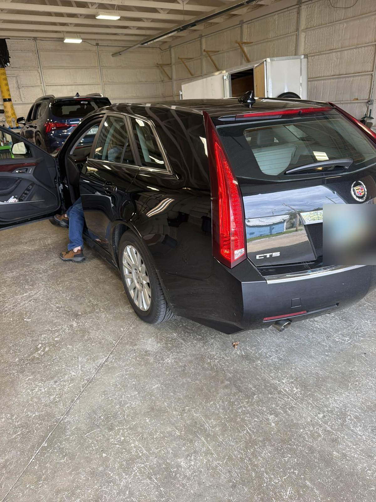 Black 2012 Cadillac CTS Sport Wagon in the 217 Dent shop, driver-side rear corner view, license plate blurred