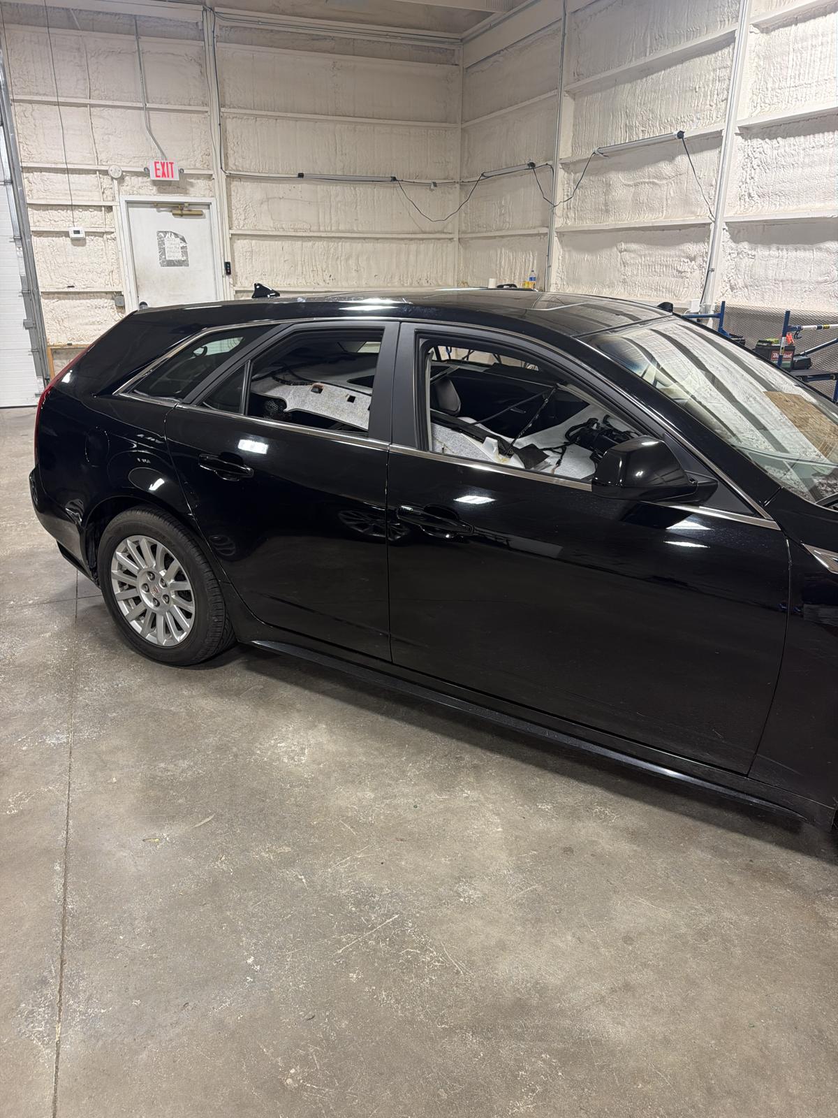 Passenger side of a black 2012 Cadillac CTS Sport Wagon in the 217 Dent shop with the headliner dropped