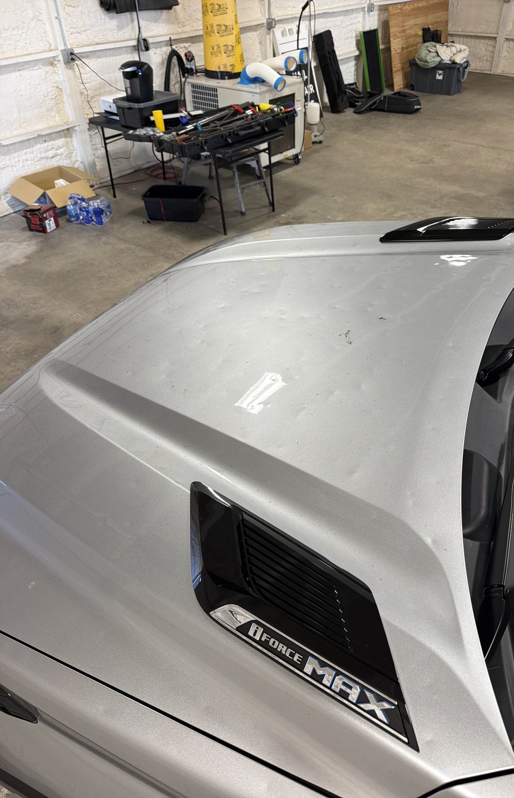 Aluminum hood of a silver 2024 Toyota Tundra with hail dents visible across the surface