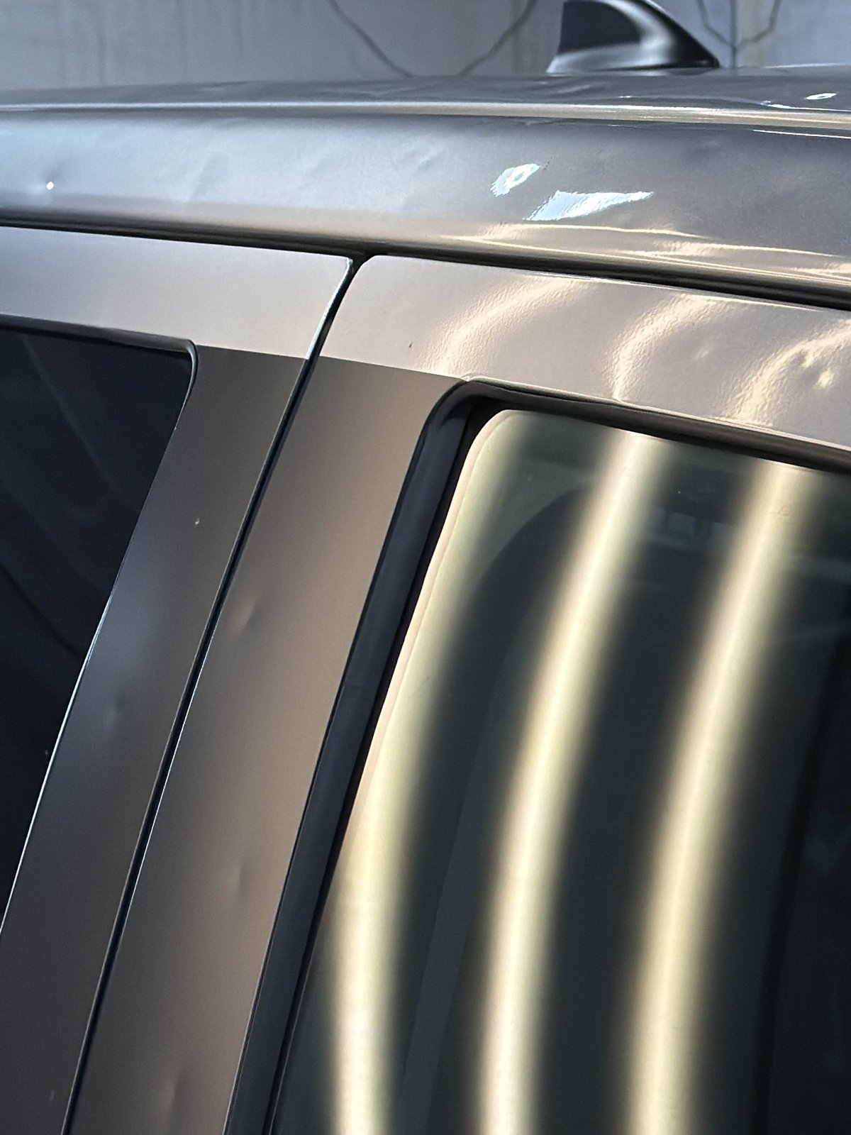 Upper passenger front door frame of a silver 2024 Toyota Tundra with a PDR light board reflected in the glass
