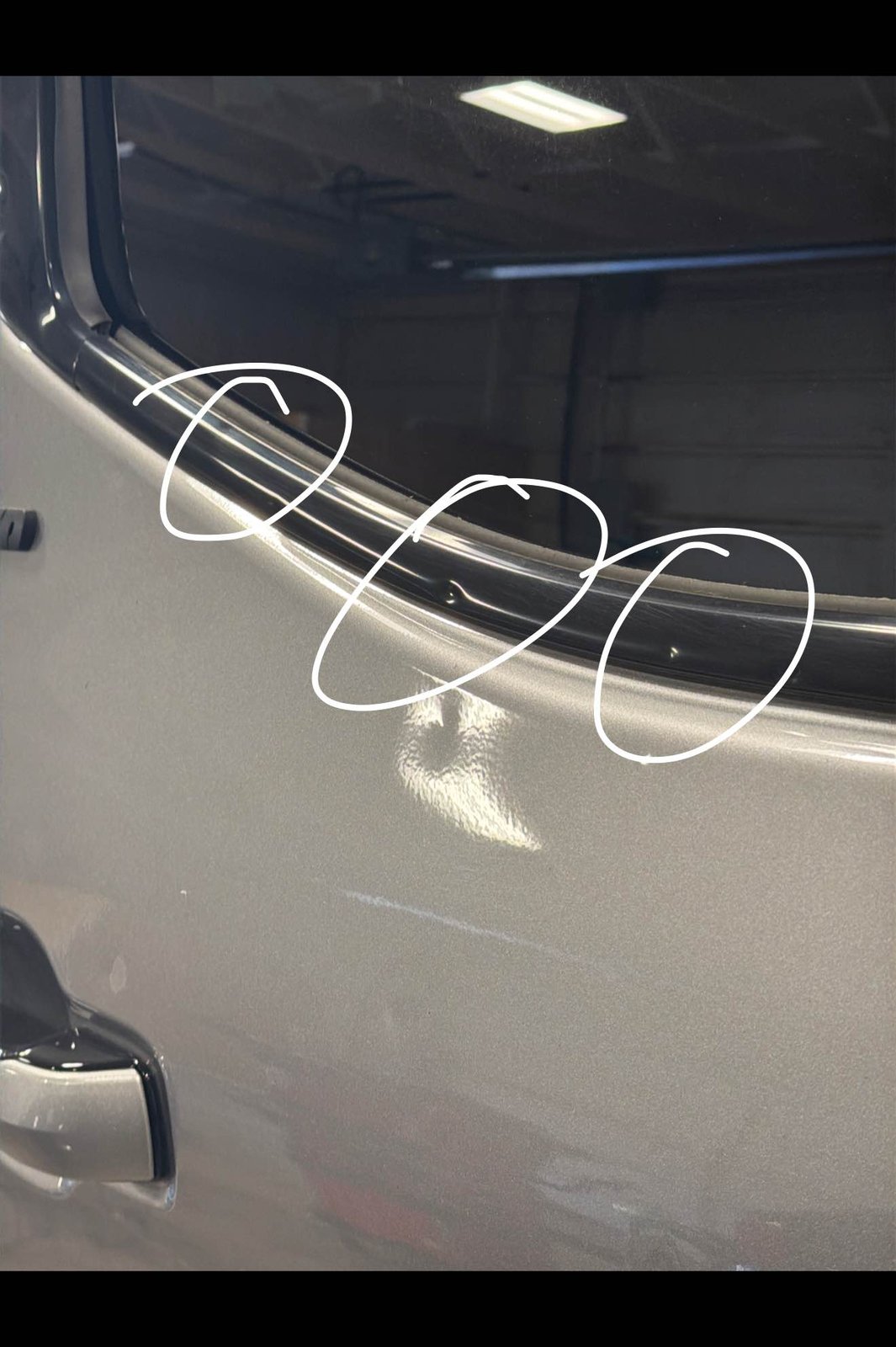 Passenger rear door of a silver 2024 Toyota Tundra with dents circled by the technician