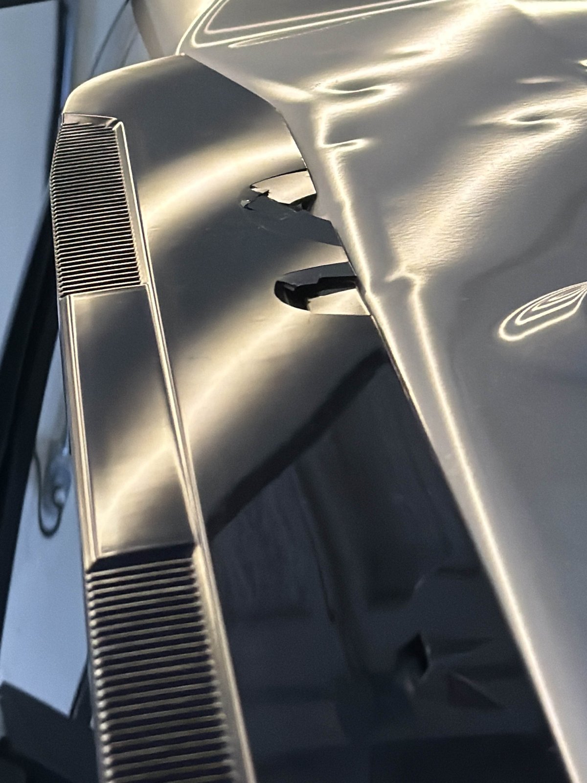 Roof edge of a silver 2024 Toyota Tundra with hail dents in the reflection
