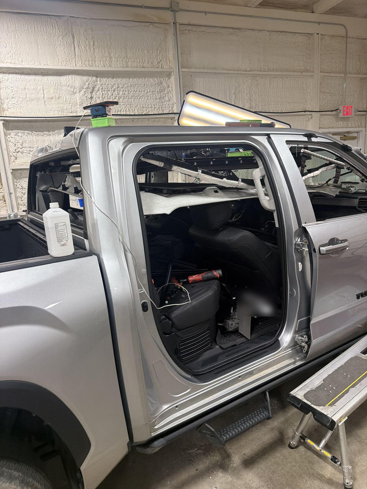 Silver 2024 Toyota Tundra in the 217 Dent shop with the rear door open, the headliner dropped and a PDR light board on the roof