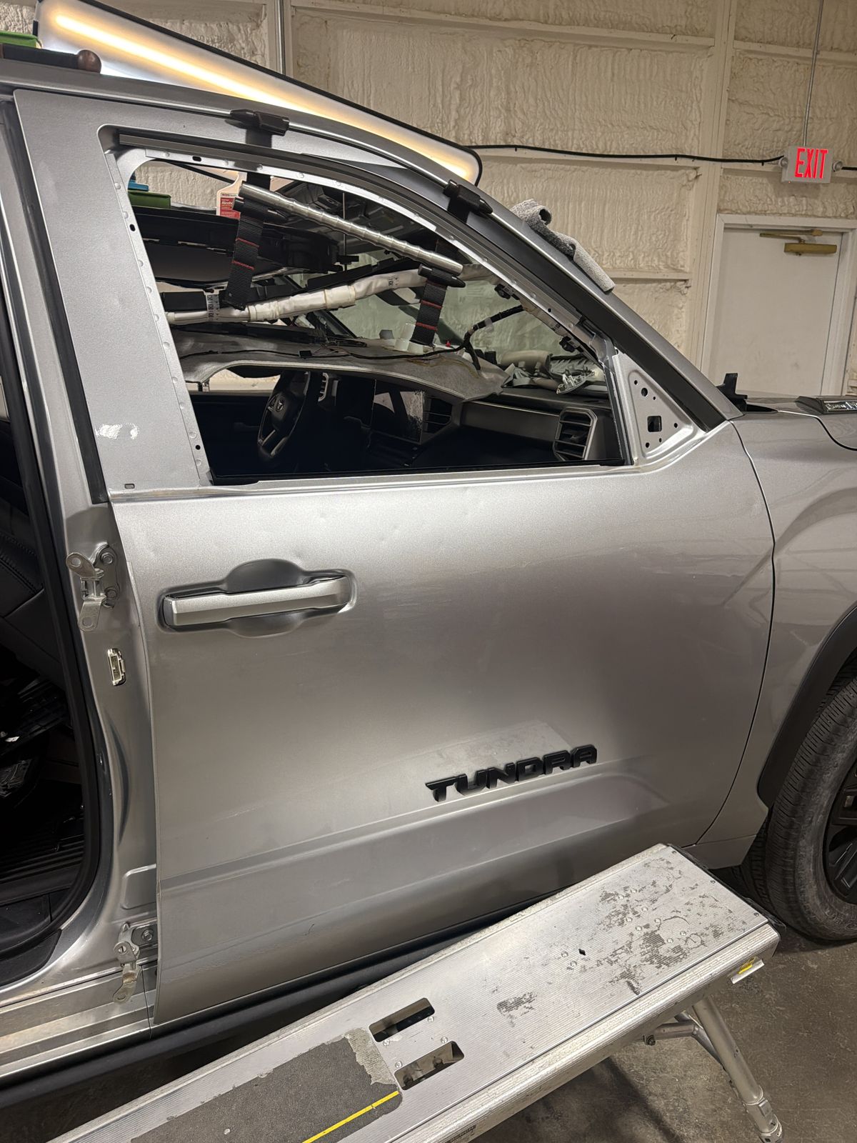 Front aluminum door of a silver 2024 Toyota Tundra with the TUNDRA badge and the door glass removed, in the 217 Dent shop