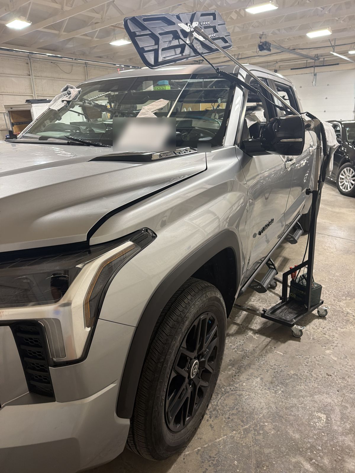 Front corner view of a silver 2024 Toyota Tundra with a PDR light on a stand at the windshield