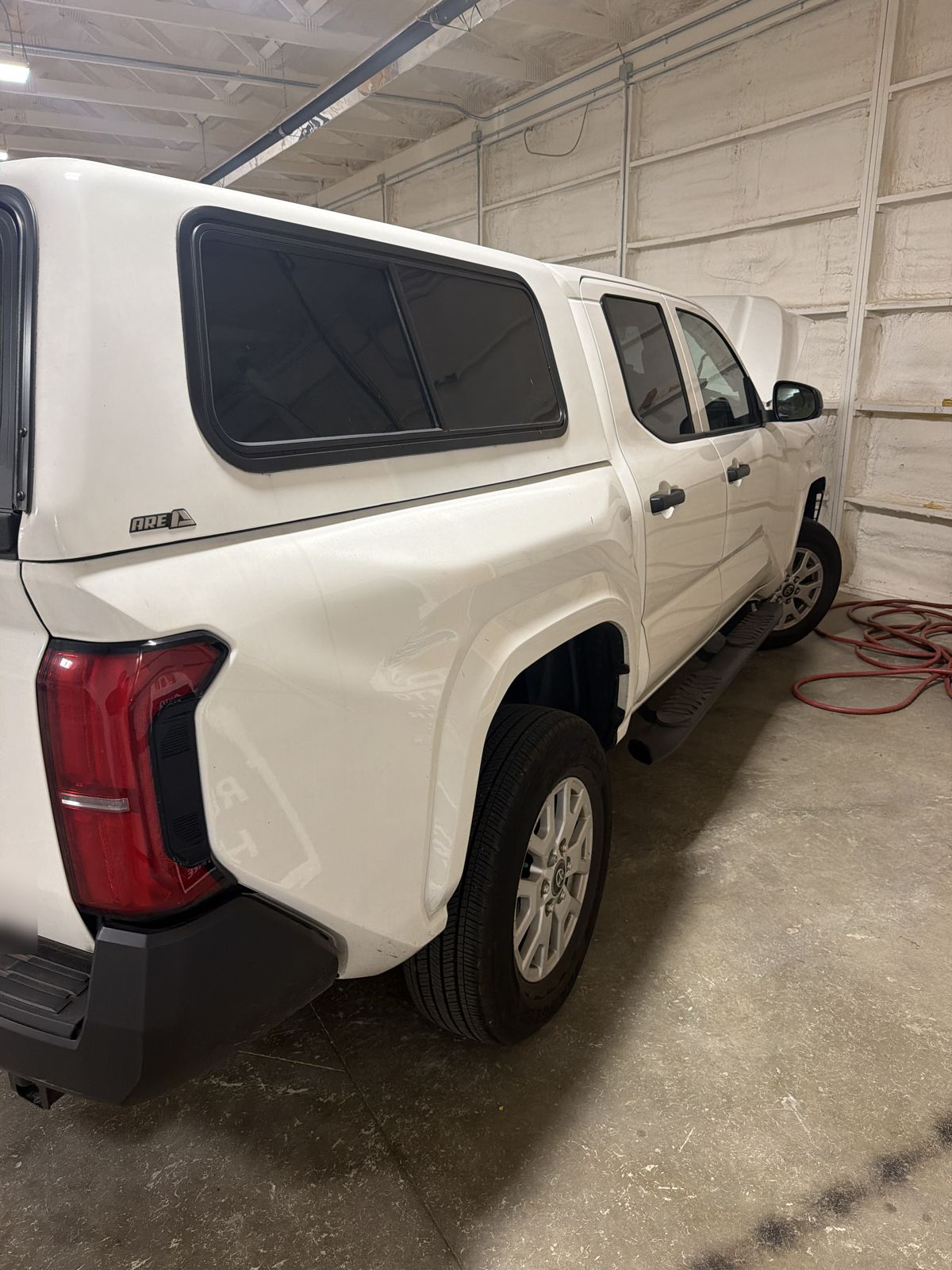 White 2025 Toyota Tacoma SR in the 217 Dent shop, driver-side rear corner view