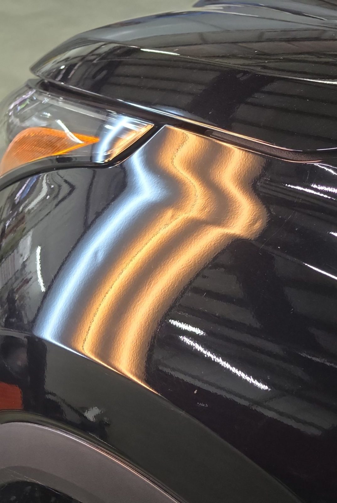 Top of the driver fender of a black 2025 Toyota Highlander Hybrid along the hood line, under PDR light