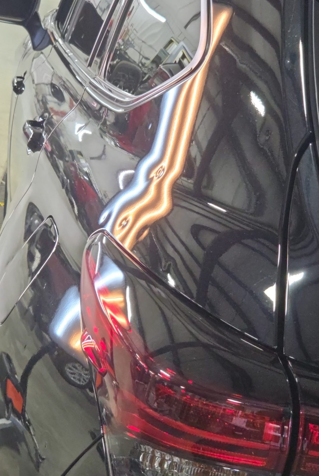 Driver rear corner of a black 2025 Toyota Highlander Hybrid above the taillight, under PDR light