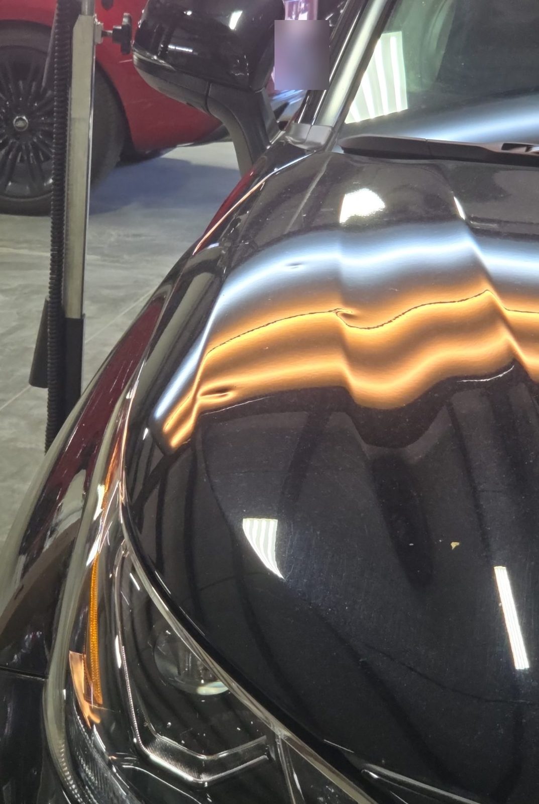 Front corner of the hood of a black 2025 Toyota Highlander Hybrid by the headlight, under PDR light