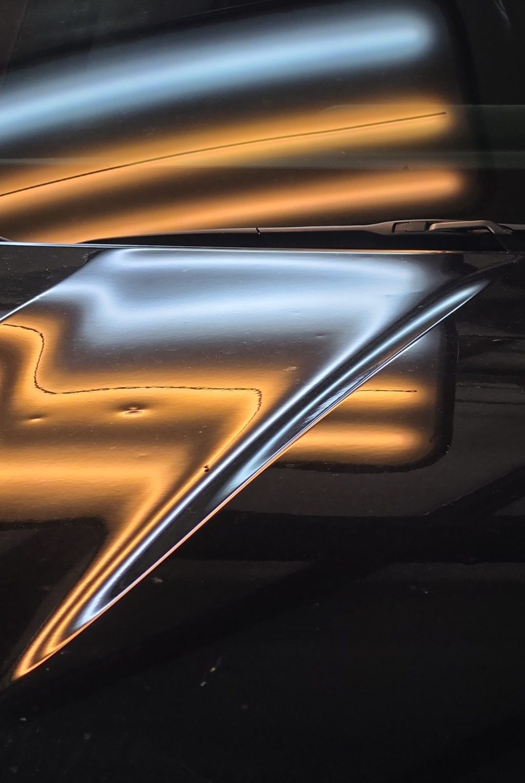 Close-up of the hood of a black 2025 Toyota Highlander Hybrid under a PDR light board