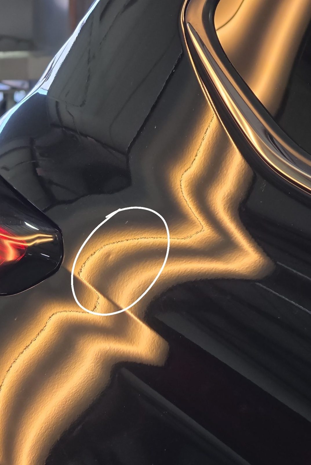 Passenger quarter panel of a black 2025 Toyota Highlander Hybrid with a dent circled by the tech