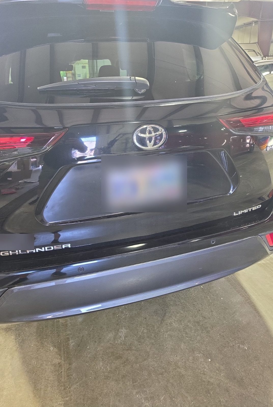 Rear liftgate and bumper of a black 2025 Toyota Highlander Hybrid, license plate and dealer sticker blurred